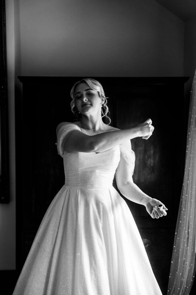 a black and white image of a bride spraying perfume