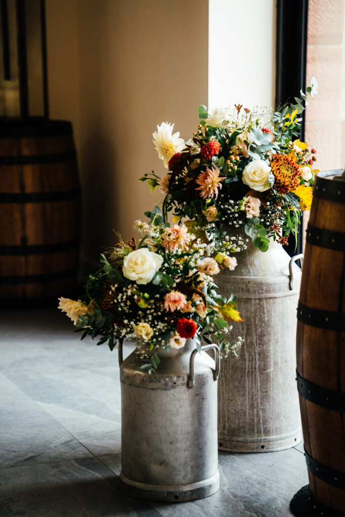 seasonal flowers in milk churns in the Cart Shed for an autumnal New House Farm wedding
